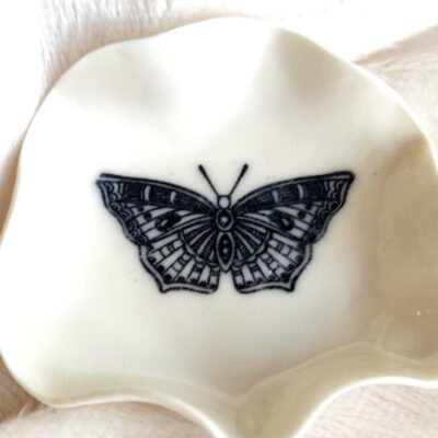A small, white scalloped "Butterfly Ring Holder" featuring a black butterfly design (6.5 cm x 6.5 cm).