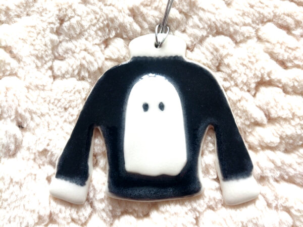 Porcelain Ghost Jumper pendant featuring a black sweater design with a white ghost on a textured white background. Porcelain Ghost Jumper pendant featuring a black sweater design with a white ghost on a textured white background.