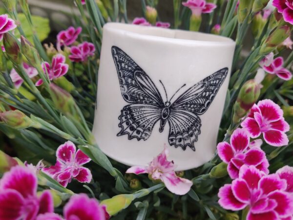 Enchanted Butterfly Porcelain Tealight Holder featuring a black butterfly motif amidst vibrant pink flowers.